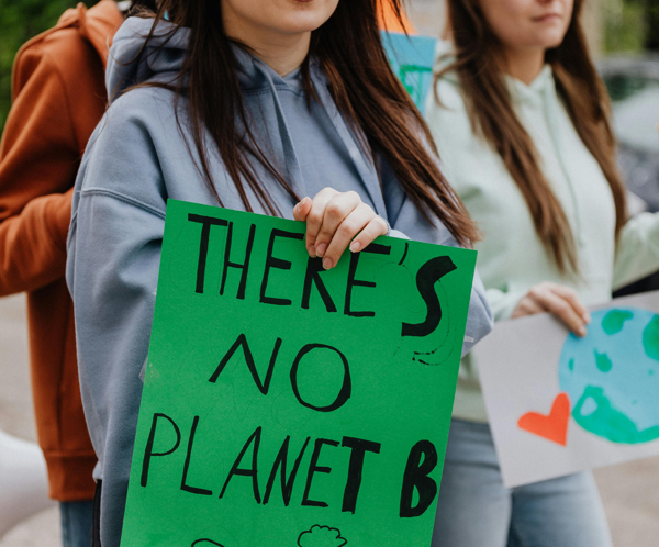Youth at climate protest rally, holding signs for environmental awareness and change.
