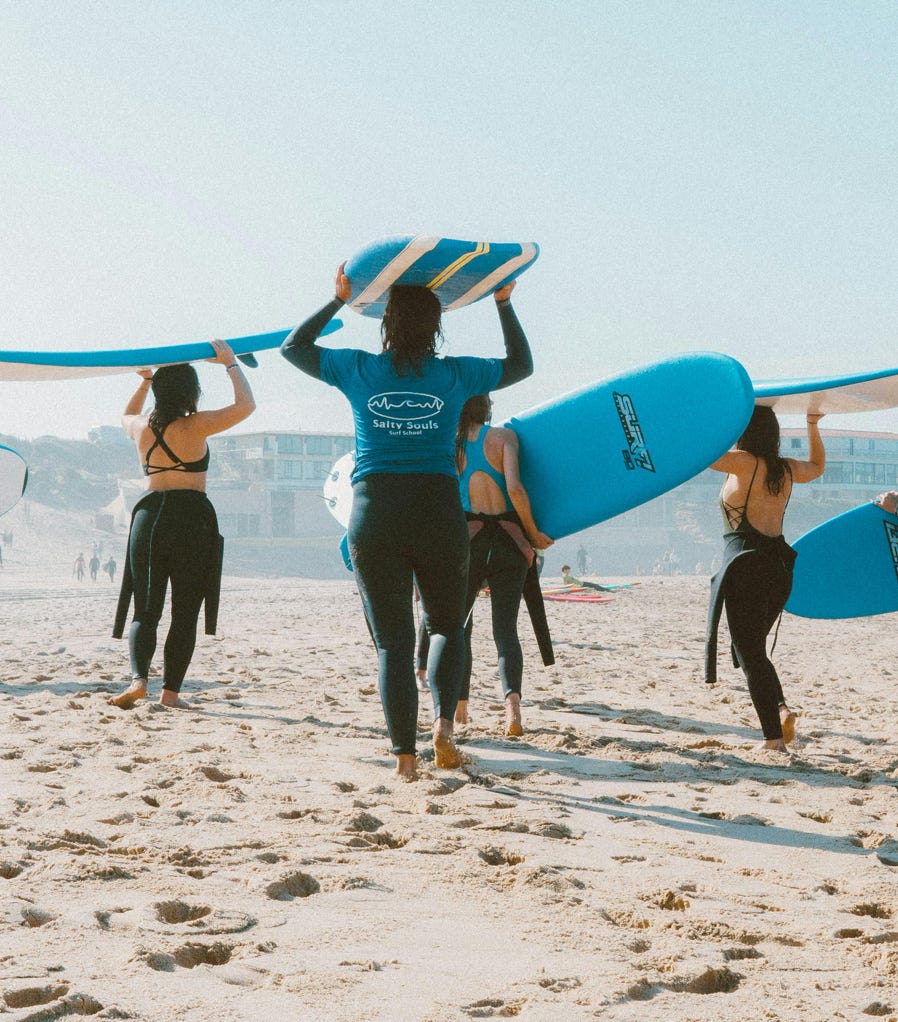 Group of surfers with blue surfboards heading to the ocean on a sunny beach.