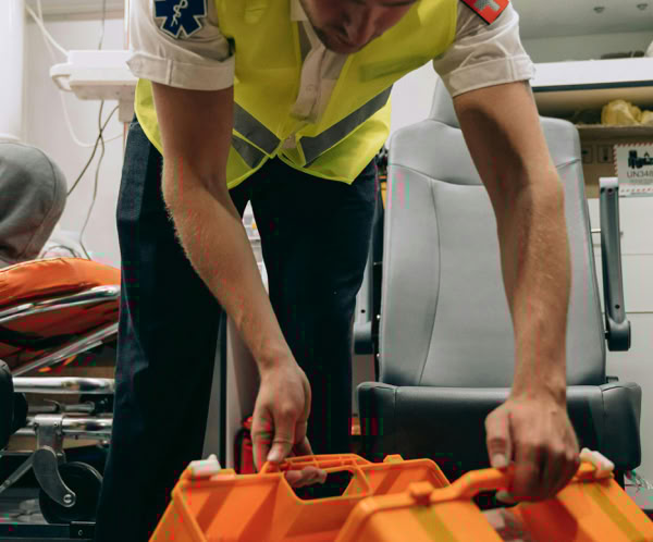 Paramedic arranging equipment inside an ambulance, ensuring readiness for emergencies.